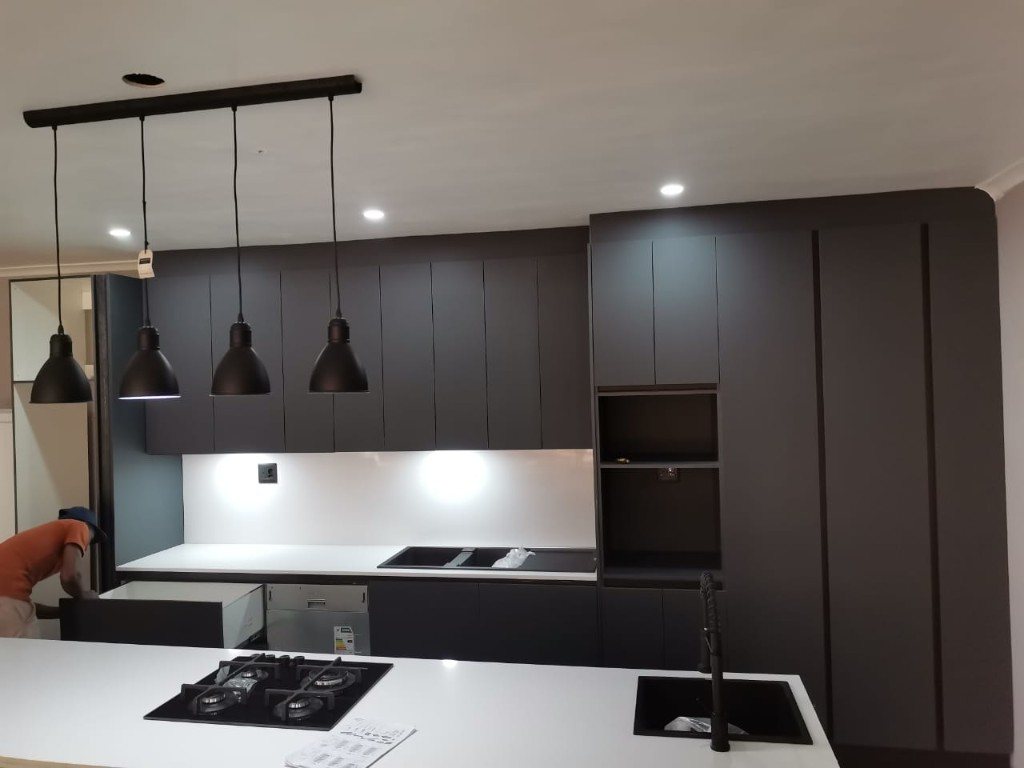 Charcoal handleless kitchen with island hob, sink and black pendants