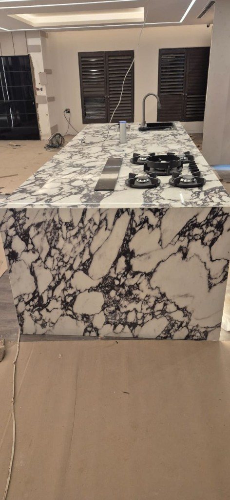 Heavily veined marble waterfall island with hob and sink