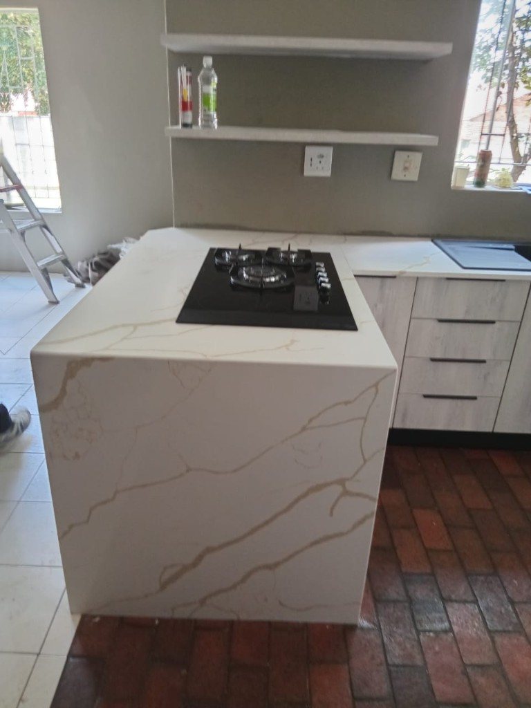 White stone waterfall island with a gas hob