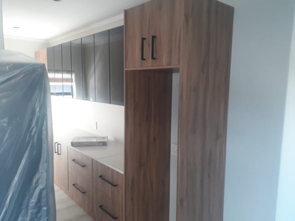 Wood-grain run with glossy dark uppers and a fridge housing