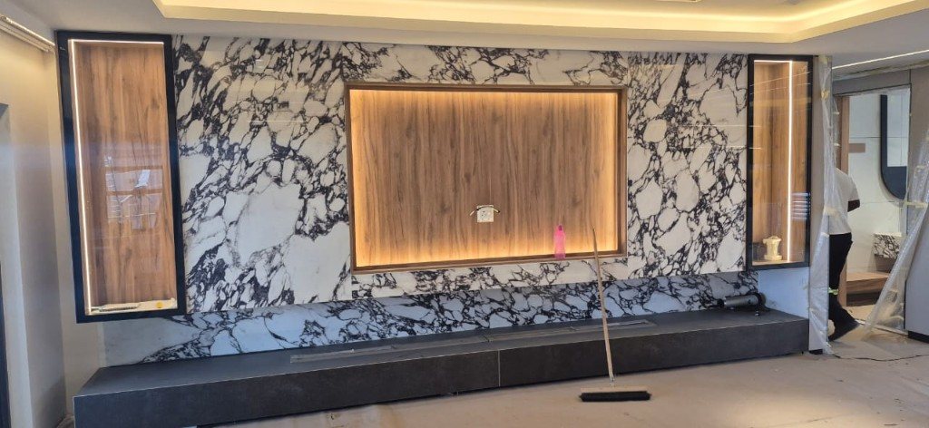 Marble media wall with a lit wood TV niche and glass side cabinets