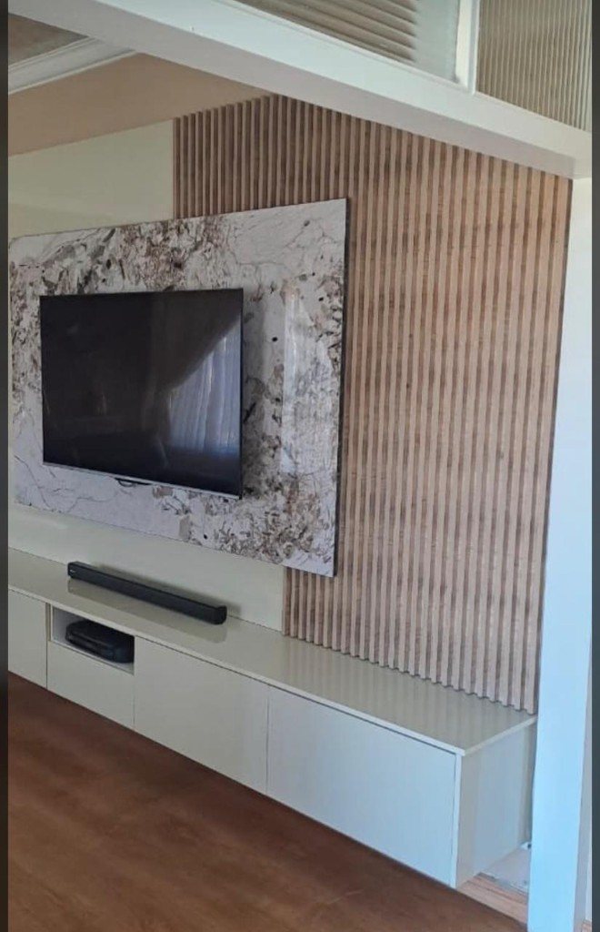 TV mounted on a veined stone panel with timber slats behind