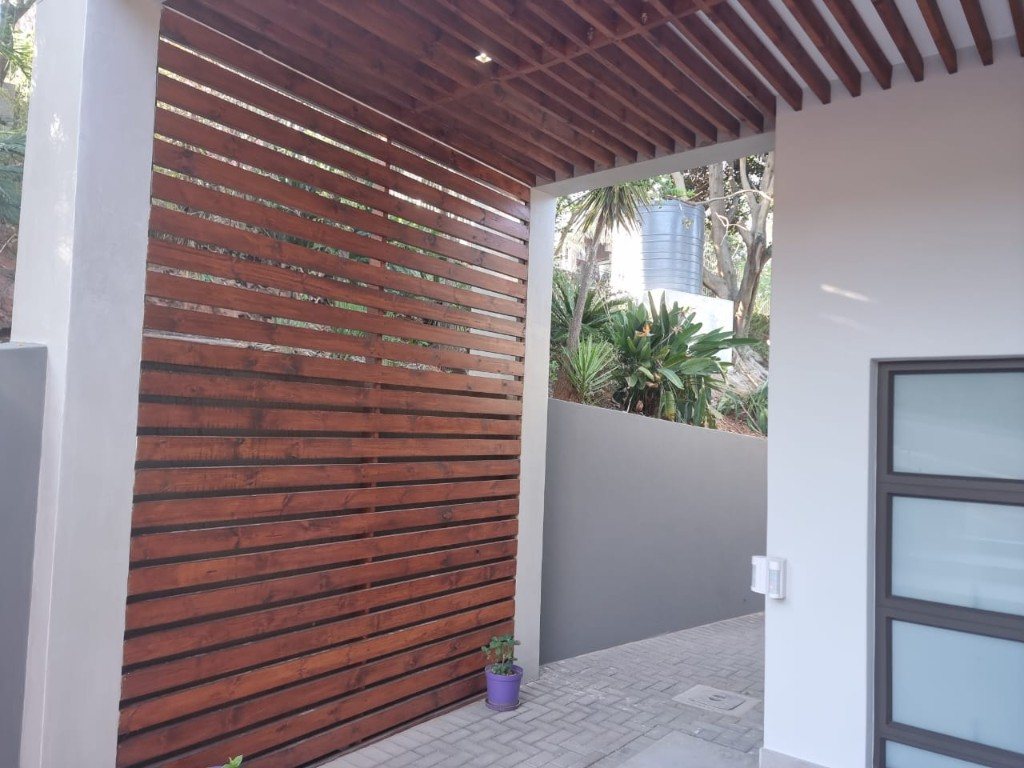 Outdoor timber slat screen and matching slat ceiling with a recessed light